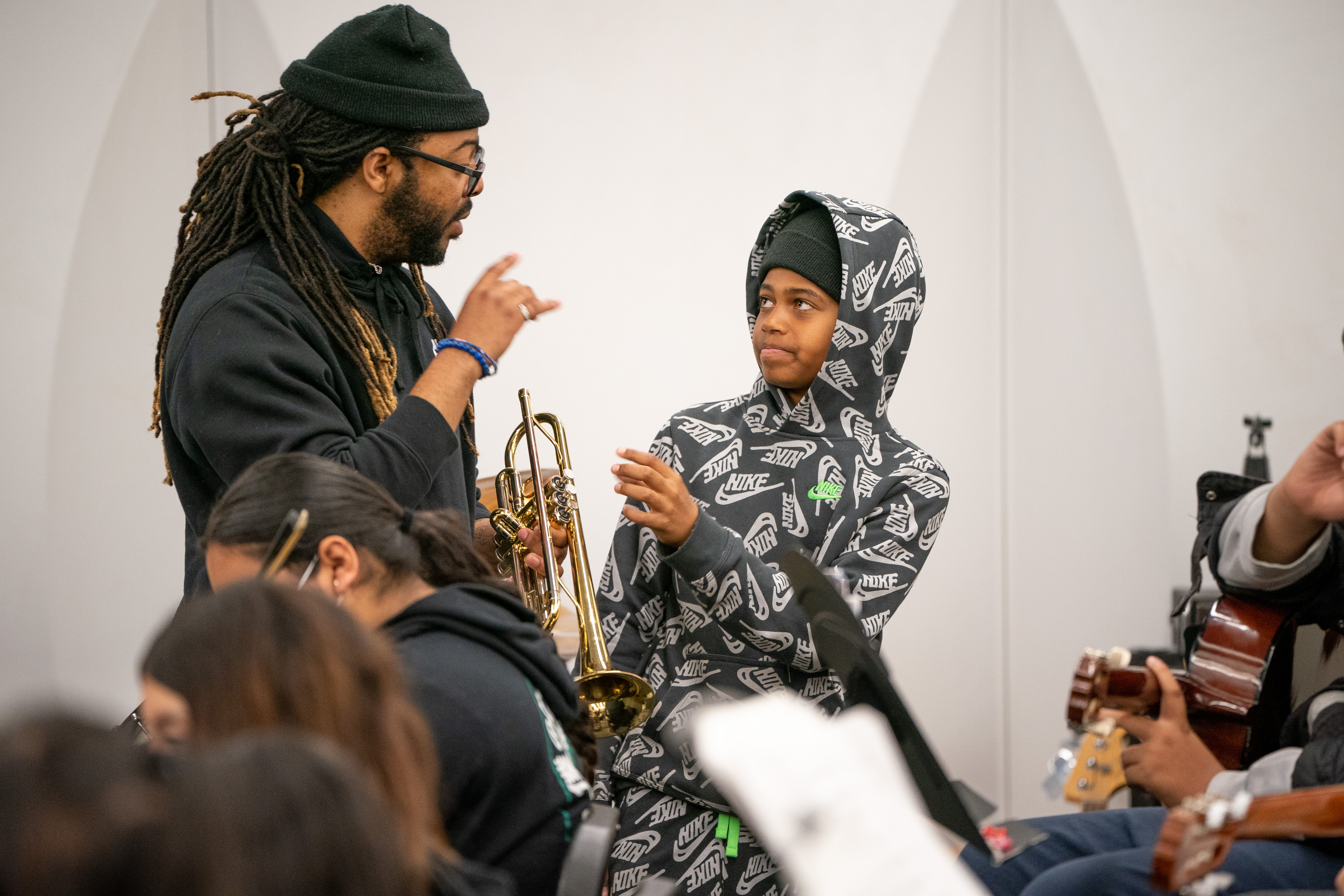 music teacher holding trumpet with one student